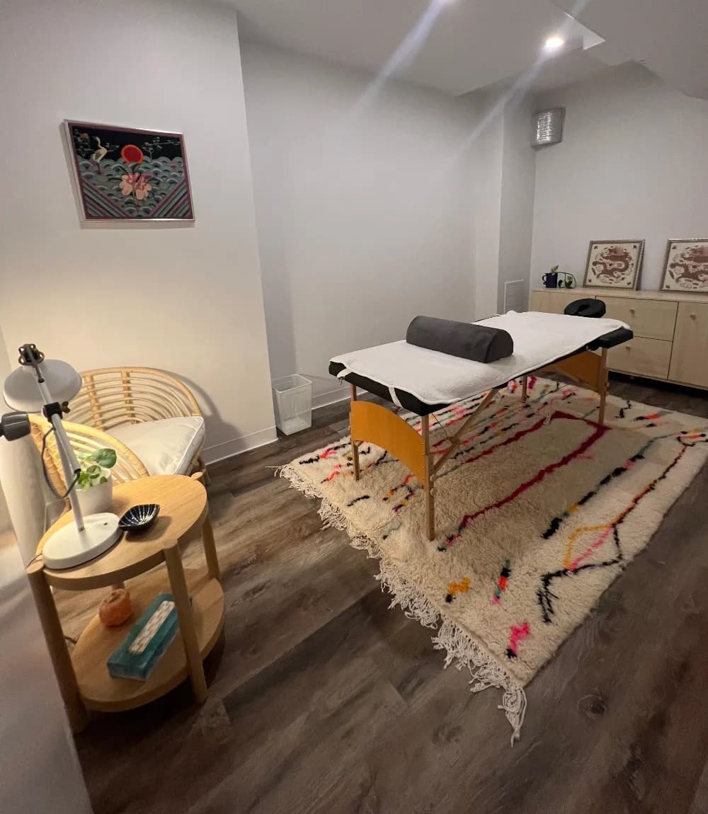 Massage table on a colorful shaggy rug in a serene therapy room with wooden floors.